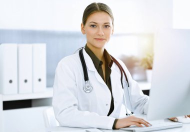 Sunny Hastanesi 'nde otururken bilgisayarında daktilo yazan kadın doktor. Tıp ve sağlık alanlarındaki veriler