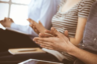 İş adamları toplantı ya da konferansta el çırpıyor. Modern beyaz ofisteki bir grup tanınmayan iş adamı ve kadın. Başarı takım çalışması, kurumsal koçluk ve alkış konsepti