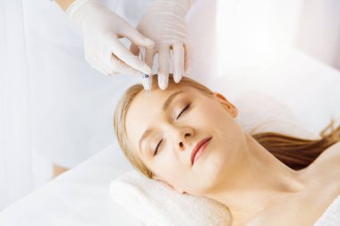 Güzellik doktoru, beyaz kadın yüzüne şırıngayla güzellik prosedürü uyguluyor. Kozmetik tıp ve cerrahi, güzellik enjeksiyonları konsepti