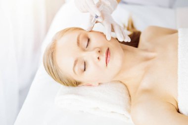 Güzellik doktoru, beyaz kadın yüzüne şırıngayla güzellik prosedürü uyguluyor. Kozmetik tıp ve cerrahi, güzellik enjeksiyonları konsepti