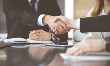 Bilinmeyen işadamları modern bir ofiste cam masanın üstünde el sıkışıyor. Toplantıda bilinmeyen iş adamları var. Takım çalışması, ortaklık ve el sıkışma kavramı