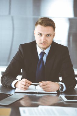 Modern ofiste iş adamı vesikalığı. Bilinmeyen girişimci arka planda meslektaşlarıyla oturuyor. Takım çalışması ve ortaklık kavramı