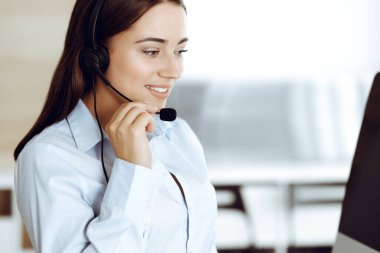 Esmer kadın müşteri hizmetleri temsilcisi internet üzerinden müşterilere danışıyor. Çağrı merkezi ve iş adamları kavramı