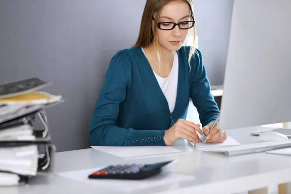 Contabilista verificando ficha financeira ou contando por calculadora de renda para a forma de imposto, mãos close-up. Mulher de negócios sentada e trabalhando na mesa no escritório. Conceito de auditoria — Fotografia de Stock