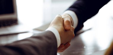 Bilinmeyen işadamı, modern ofiste iş arkadaşı ya da ortağıyla el sıkışıyor. Toplantıda iş adamları grubu