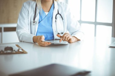 Bilinmeyen kadın doktor klinikte duruyor ve tablet bilgisayar kullanıyor, yakın plan. Veriler ve tıp ve sağlık hizmetlerindeki en iyi hizmet