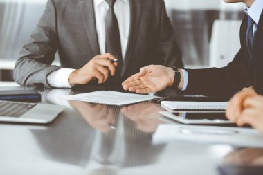 Bilinmeyen iş adamları modern ofiste birlikte çalışıyorlar, yakın plan. İş adamı ve kadın iş arkadaşları veya avukatlarıyla pazarlıkta sözleşmeyi tartışıyor