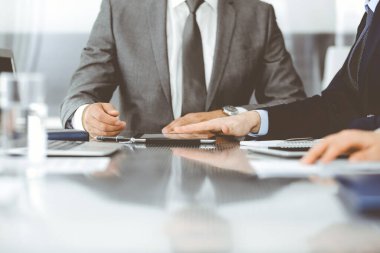 Bilinmeyen işadamı, modern ofisteki cam masada otururken tablet bilgisayar kullanıyor ve iş arkadaşıyla birlikte çalışıyor. Takım çalışması ve ortaklık kavramı