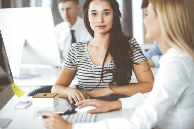 Bir grup iş adamı toplantıda soruları tartışıyor. Ofis görüşmelerinde iş arkadaşına gülümseyen sıradan giyinmiş iş kadınının vesikalığı. Şirket içinde takım çalışması ve işbirliği