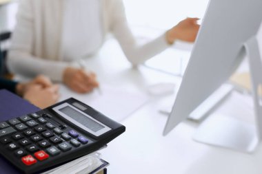 Hesap makinesi ve kağıtlar iş kadını ya da ofisteki büroda çalışan muhasebeci tarafından incelenmeyi bekliyor. İç Denetim ve vergi kavramı