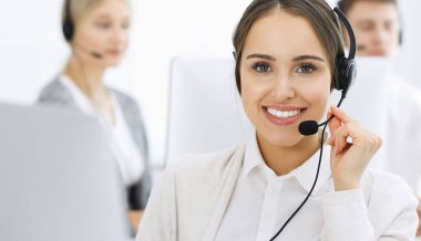 Merkezi ara. Çeşitli operatörler iş başında. Telepazarlama servisinin müşterileriyle iletişim kuran kulaklıklı güzel bir kadın. İş konsepti