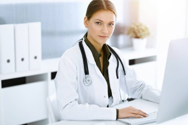 Sunny Hastanesi 'nde otururken bilgisayarında daktilo yazan kadın doktor. Tıp ve sağlık alanlarındaki veriler