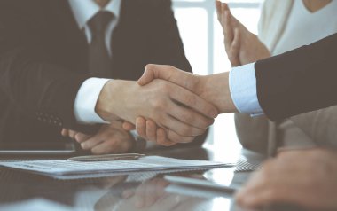 Modern ofiste iş adamları kontrat imzalandıktan sonra el sıkışıyor. Takım çalışması ve el sıkışma kavramı