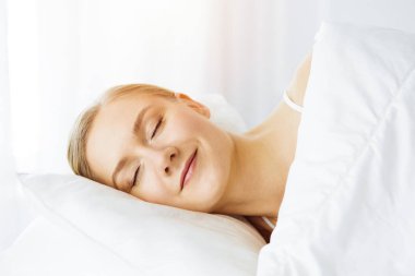 Güzel genç bir kadın yatak odasında rahat ve mutlu bir şekilde uyuyor.