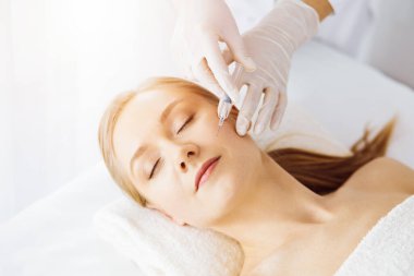 Güzellik doktoru, beyaz kadın yüzüne şırıngayla güzellik prosedürü uyguluyor. Kozmetik tıp ve cerrahi, güzellik enjeksiyonları konsepti