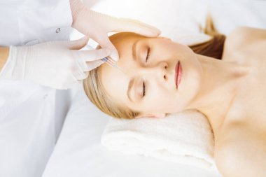 Güzellik doktoru, beyaz kadın yüzüne şırıngayla güzellik prosedürü uyguluyor. Kozmetik tıp ve cerrahi, güzellik enjeksiyonları konsepti