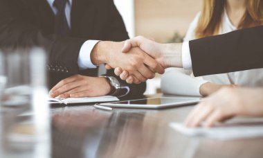 Bilinmeyen işadamları modern bir ofiste cam masanın üstünde el sıkışıyor. Toplantıda bilinmeyen iş adamları var. Takım çalışması, ortaklık ve el sıkışma kavramı