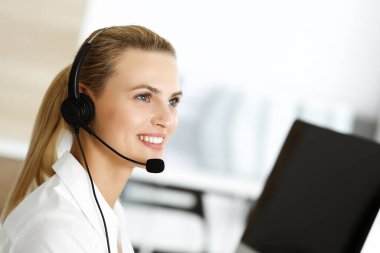 Sarışın kadın müşteri hizmetleri temsilcisi müşterilerine kulaklık kullanarak danışmanlık yapıyor. Çağrı merkezi ve iş konsepti