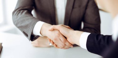 Bilinmeyen işadamı, modern ofiste iş arkadaşı ya da ortağıyla el sıkışıyor. Toplantıda iş adamları grubu