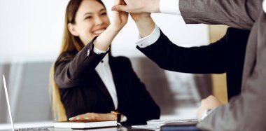 Bilinmeyen iş adamları modern ofiste el ele tutuşuyor. İş adamları ve kadınlar elleriyle bir takım olarak daire çiziyorlar, yakın plan.