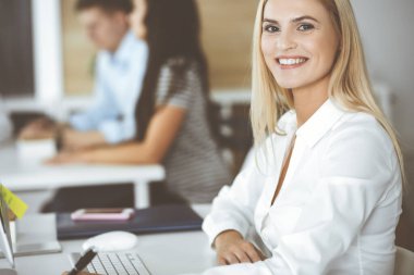 Modern ofisteki işyerinde bilgisayar kullanan bir iş kadını. Sekreter ya da kadın avukat gülümsüyor ve mutlu görünüyor. Zevk ve başarı için çalışmak