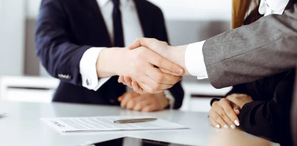 Empresário desconhecido apertando as mãos com seu colega ou parceiro acima da mesa de vidro no escritório moderno, close-up. Grupo de empresários em reunião — Fotografia de Stock