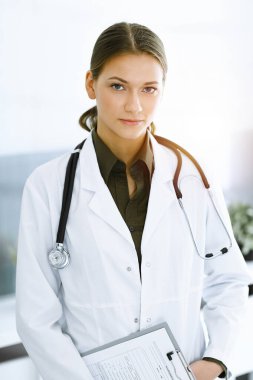 Güneşli klinikte durup kameraya bakan kadın doktor. İlaç ve sağlık hizmetleri