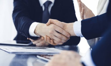 Modern ofiste iş adamları kontrat imzalandıktan sonra el sıkışıyor. Takım çalışması, ortaklık ve el sıkışma kavramı