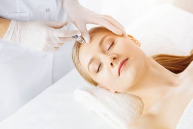 Güzellik doktoru, beyaz kadın yüzüne şırıngayla güzellik prosedürü uyguluyor. Kozmetik tıp ve cerrahi, güzellik enjeksiyonları konsepti