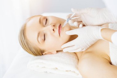 Güzellik doktoru, beyaz kadın yüzüne şırıngayla güzellik prosedürü uyguluyor. Kozmetik tıp ve cerrahi, güzellik enjeksiyonları konsepti