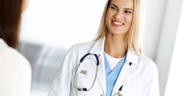 Hastanedeki kadın-doktor kadın hastayla seve seve iletişim kurar. Sarışın doktor tıbbi geçmişi ve muayene sonuçlarını kontrol ediyor. Tıp konsepti