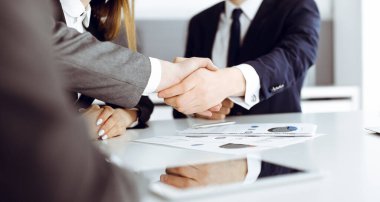 Bilinmeyen işadamı, modern ofiste iş arkadaşı ya da ortağıyla el sıkışıyor. Toplantıda iş adamları grubu