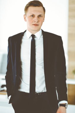 Ofisteki kameraya bakıp duran neşeli iş adamı. Genç ve başarılı girişimcinin vesikalığı