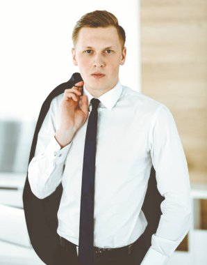 Ofisteki kameraya bakıp duran neşeli iş adamı. Genç ve başarılı girişimcinin vesikalığı