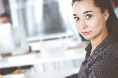 Modern ofisteki işyerinde bilgisayar kullanan bir iş kadını. Esmer sekreter ya da kadın avukat kameraya bakıyor ve mutlu gülümsüyor. Zevk ve başarı için çalışmak