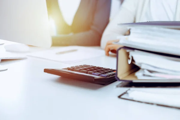 Boekhouder controleren van de jaarrekening of tellen door calculator inkomen voor belastingformulier, handen closeup. Zakenvrouw zit en werkt met collega aan het bureau. Begrip belasting- en auditsysteem — Stockfoto