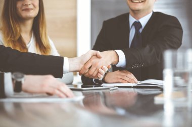 Bilinmeyen işadamları modern bir ofiste cam masanın üstünde el sıkışıyor. Toplantıda bilinmeyen iş adamları var. Takım çalışması, ortaklık ve el sıkışma kavramı