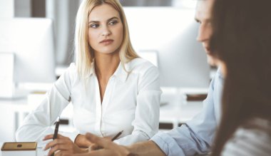 Bir grup iş adamı toplantıda soruları tartışıyor. Ofis görüşmelerinde iş arkadaşına gülümseyen sarışın iş kadınının vesikalığı. Şirket işgalinde takım çalışması ve işbirliği