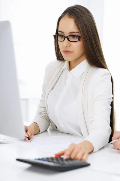 Young business woman and man sitting and working with computer and calculator in office. Bookkeeper checking balance or making finance report. Tax and audit concepts — Stock Photo, Image