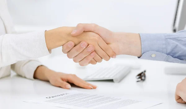 Casual dressed businessman and woman shaking hands after contract signing in white colored office. Handshake concept — Stock Photo, Image