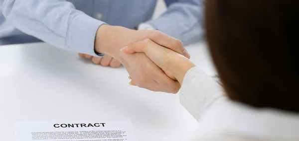 Uomo d'affari vestito casual e donna che si stringono la mano dopo la firma del contratto in ufficio di colore bianco. Concetto di stretta di mano — Foto Stock