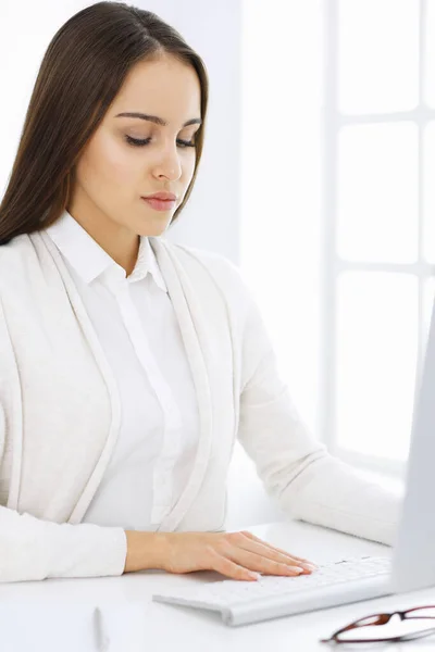 Ділова жінка сидить і працює з комп'ютером в білому офісі. Студентська дівчина вивчає або робить звіт. Концепція успіху — стокове фото