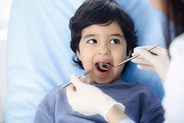 Cute árabe menino sentado na cadeira dentária com a boca aberta durante a verificação oral com o médico. Consulta ao dentista. Conceito de estomatologia — Fotografia de Stock