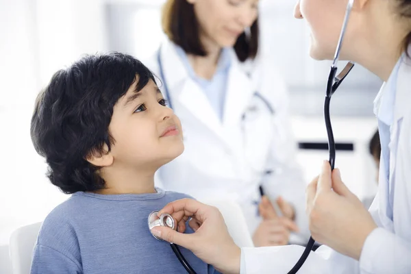 Γιατρός-γυναίκα εξετάζει ένα παιδί ασθενή με στηθοσκόπιο. Χαριτωμένο αγόρι Άραβας στο ραντεβού με γιατρό. Έννοια ιατρικής — Φωτογραφία Αρχείου