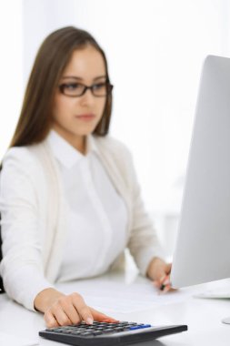 Muhasebeci hesap makinesiyle bakiyeyi kontrol ediyor ya da mali rapor hazırlıyor. Vergi ve denetim kavramları