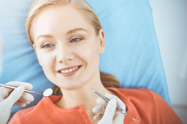 Mutlu kadın dişçi kliniğinde dişçi tarafından muayene ediliyor. Sağlıklı dişler ve ilaçlar, stomatoloji konsepti