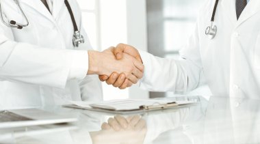 İki doktor hastaların tedavisi konusunda anlaşmak için el sıkışıyor, yakın plan. Tıbbi yardım, tıp konsepti