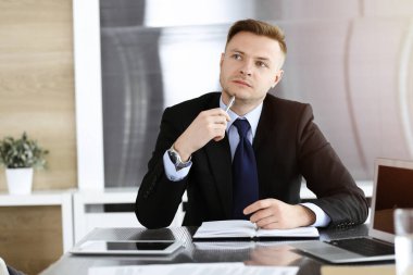 Güneşli ofiste iş adamı vesikalığı. Bilinmeyen girişimci arka planda meslektaşlarıyla oturuyor