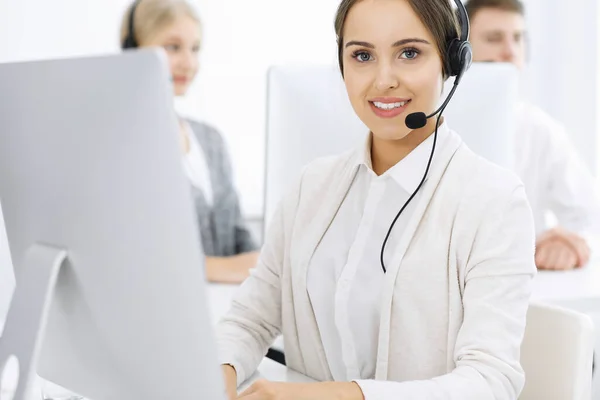 Centro de atendimento. Grupo de operadores diversos no trabalho. Mulher bonita no fone de ouvido que se comunica com os clientes do serviço de telemarketing. Conceito de negócio — Fotografia de Stock