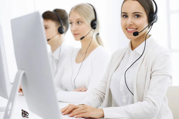 Centro de llamadas. Grupo de operadores diversos en el trabajo. Hermosa mujer en auriculares comunicándose con los clientes del servicio de telemarketing. Concepto empresarial —  Fotos de Stock